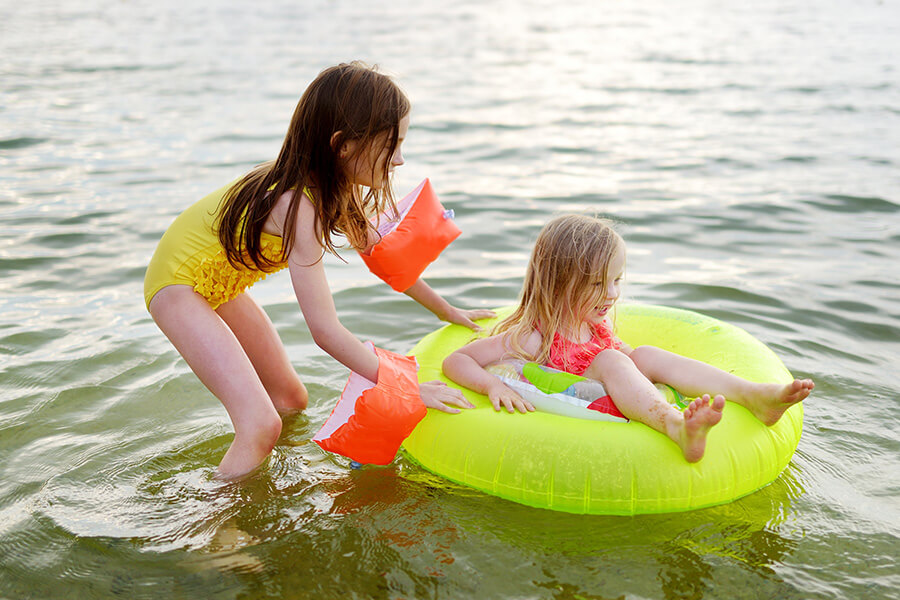 two girls playing in water with an inflatable ring